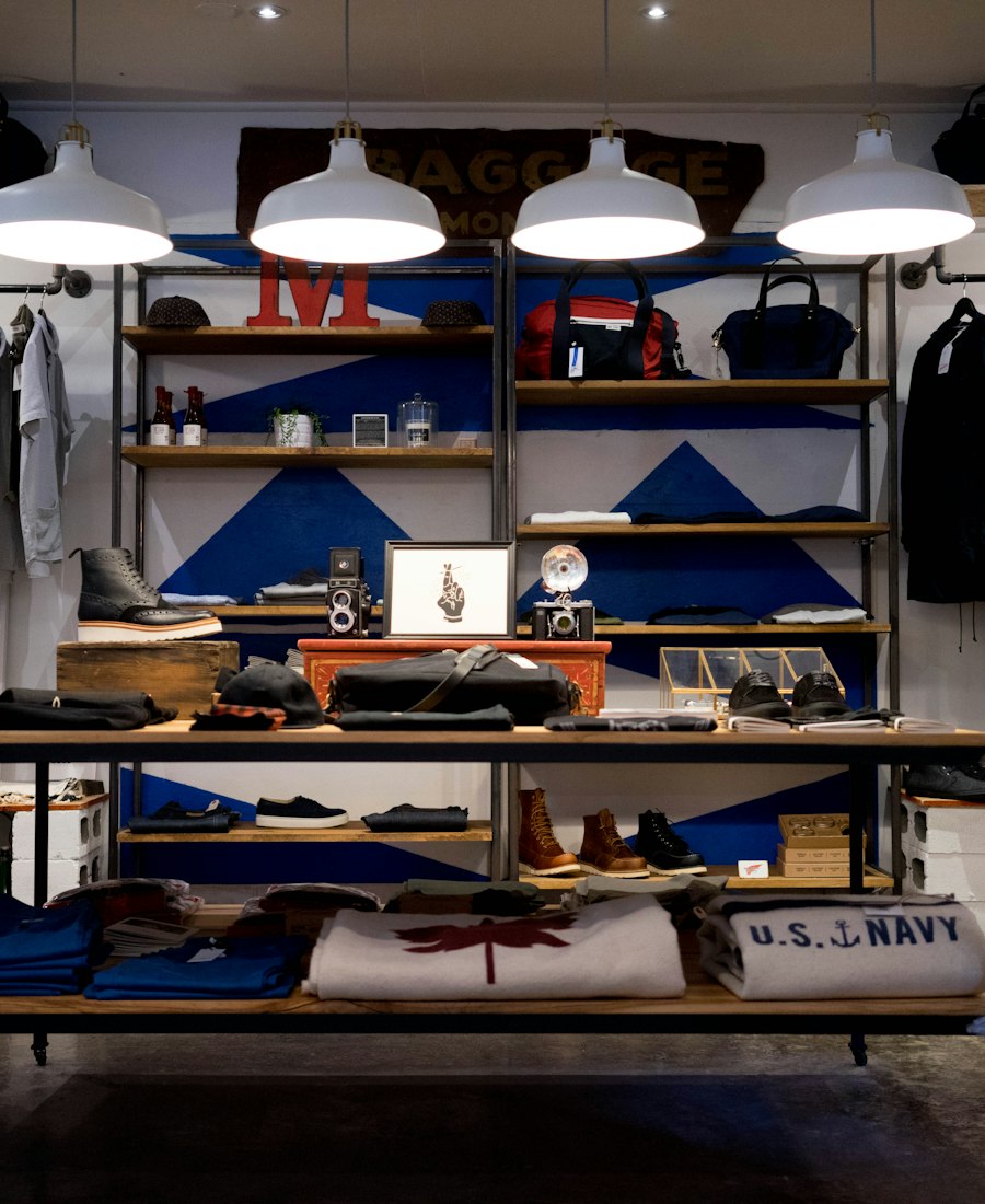 A clothing shop with shelves of folded shirts and racks of jackets